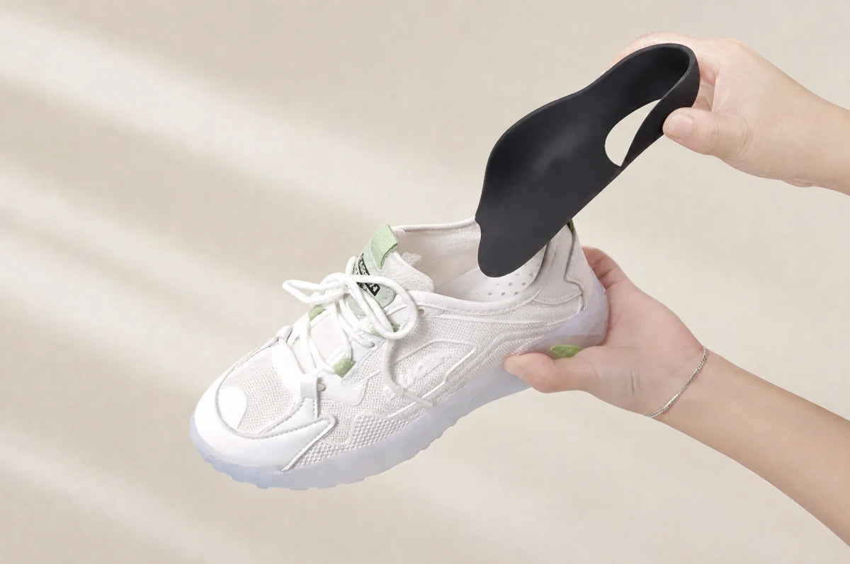 A black three-quarter-length insole positioned above an everyday sneaker